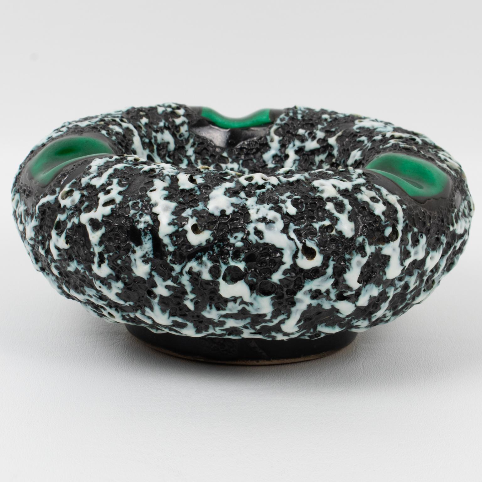 This lovely Mid-Century ceramic cigar ashtray, desk tidy, vide poche, or catchall, was crafted by Marius Giuge Atelier in Vallauris, France, in the 1960s. The puffy donut-shaped design has a lava-textured pattern in black and white colors with green