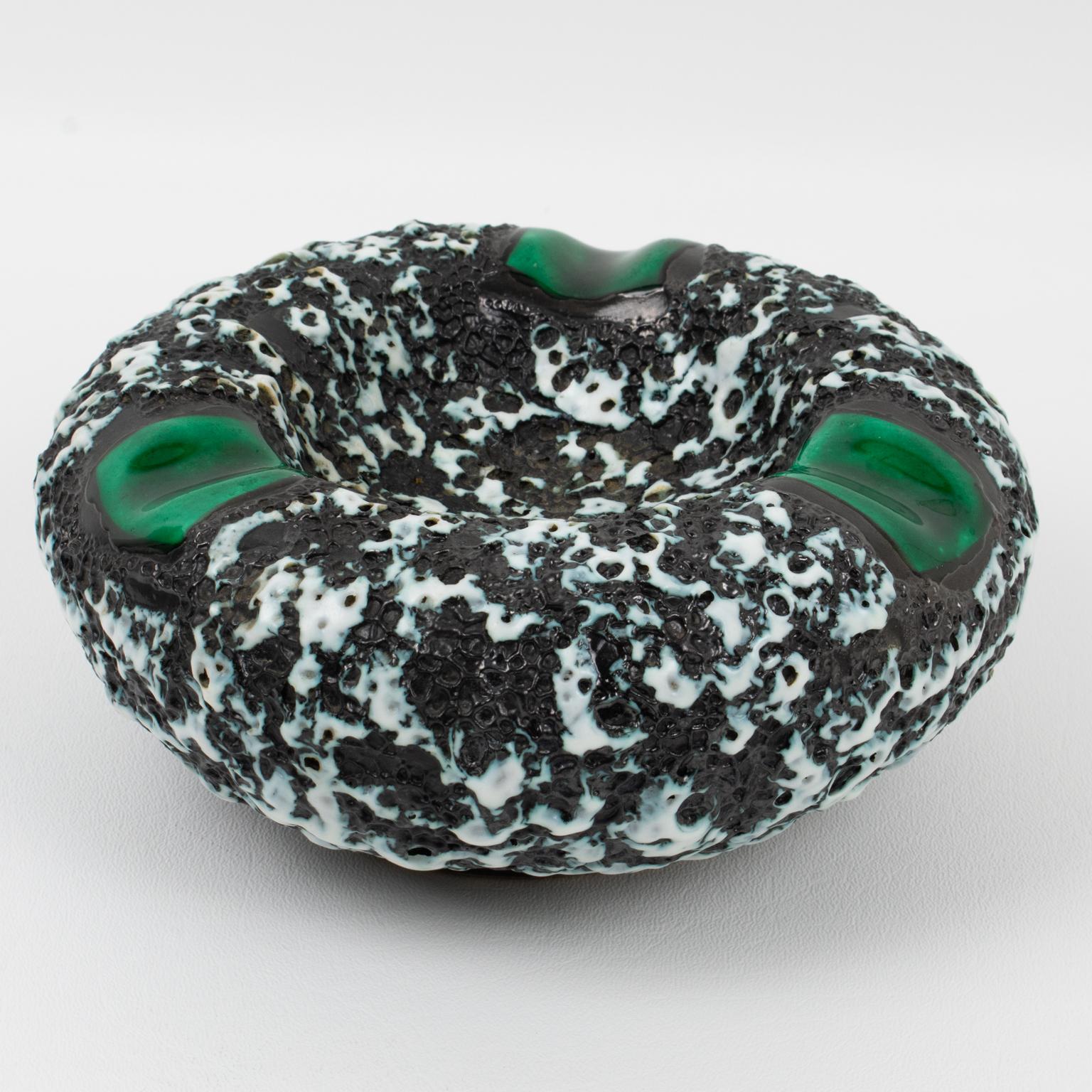 This lovely Mid-Century ceramic cigar ashtray, desk tidy, vide poche, or catchall, was crafted by Marius Giuge Atelier in Vallauris, France, in the 1960s. The puffy donut-shaped design has a lava-textured pattern in black and white colors with green