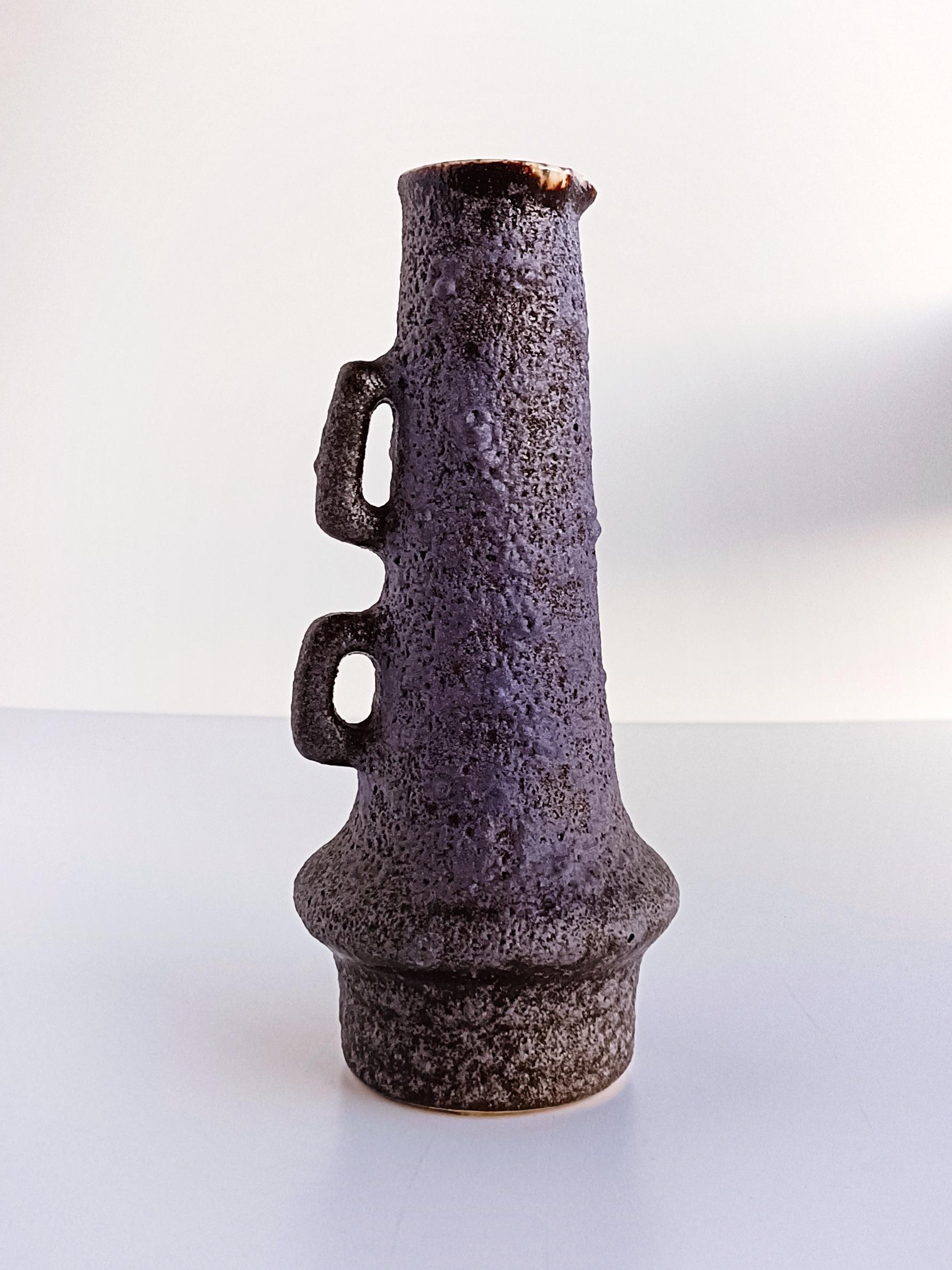 A beautiful ceramic jug featuring the lilac color Fata Lava glazing so characteristic of the Vest Ceramic studio production circa the 1960s. Marius Van Woerden focused on this type of brutalist ceramics, creating organic shapes and raw fat lava