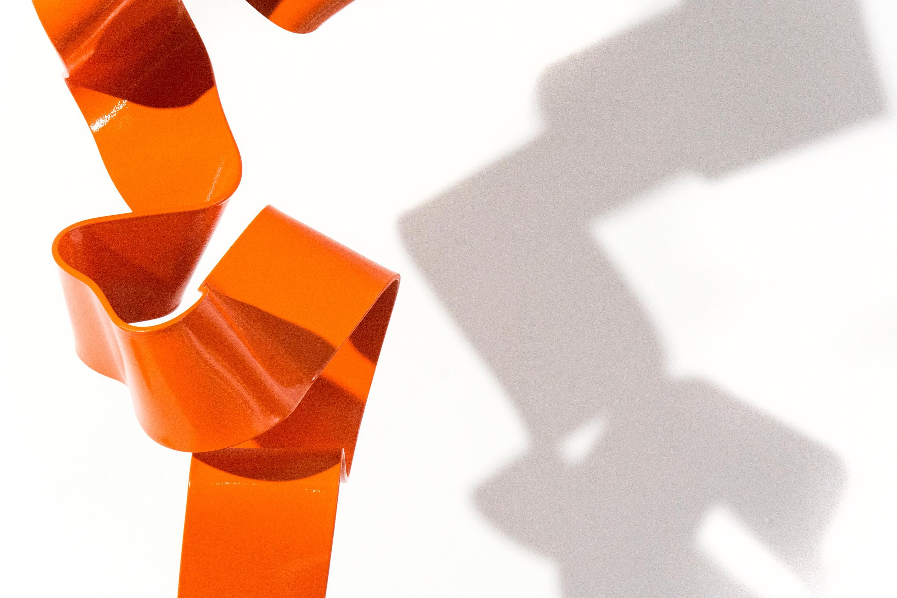 A ribbon of painted orange steel appears unwind and bounce off its base in this playful sculpture by Mark Birksted. The seeming effortlessness of this movement is belied by the physical process of making this sculpture. The artist hand bent the long