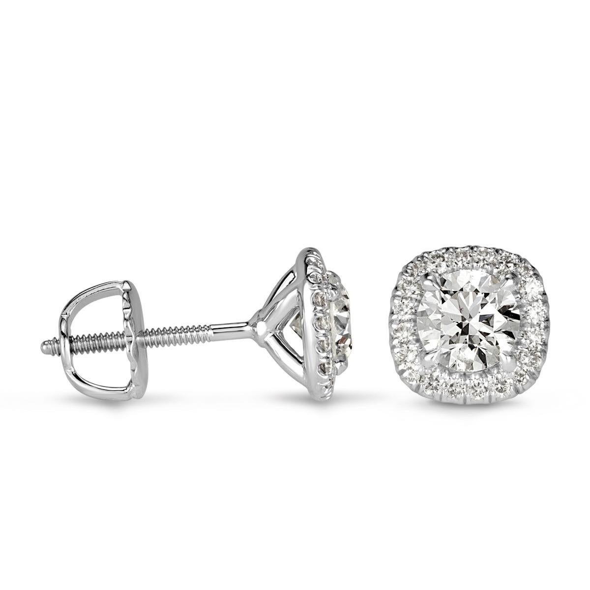 Custom created in 18k white gold, this stunning pair of diamond stud earrings showcases two round brilliant cut center diamonds each surrounded by a shimmering cushion shaped halo. They total 1.00ct in weight and are graded at E-F, VS2-SI2.
