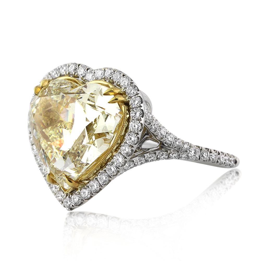This captivating diamond engagement ring features a splendid 10.39ct heart shaped center diamond, GIA certified at Fancy Yellow-SI2. It is beautifully showcased in a unique yellow gold center basket and surrounded by a matching halo of white, round
