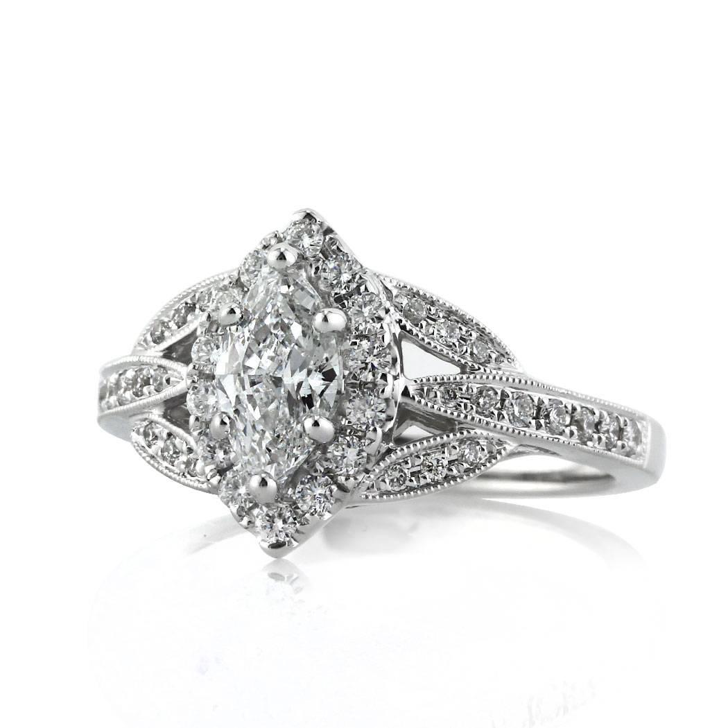 Custom created in 18k white gold, this unique diamond engagement ring features a lovely 0.70ct marquise center diamond graded at F-VS2.It is accented by a matching halo of round brilliant cut diamonds as well as a leaf shaped split shank pavé set