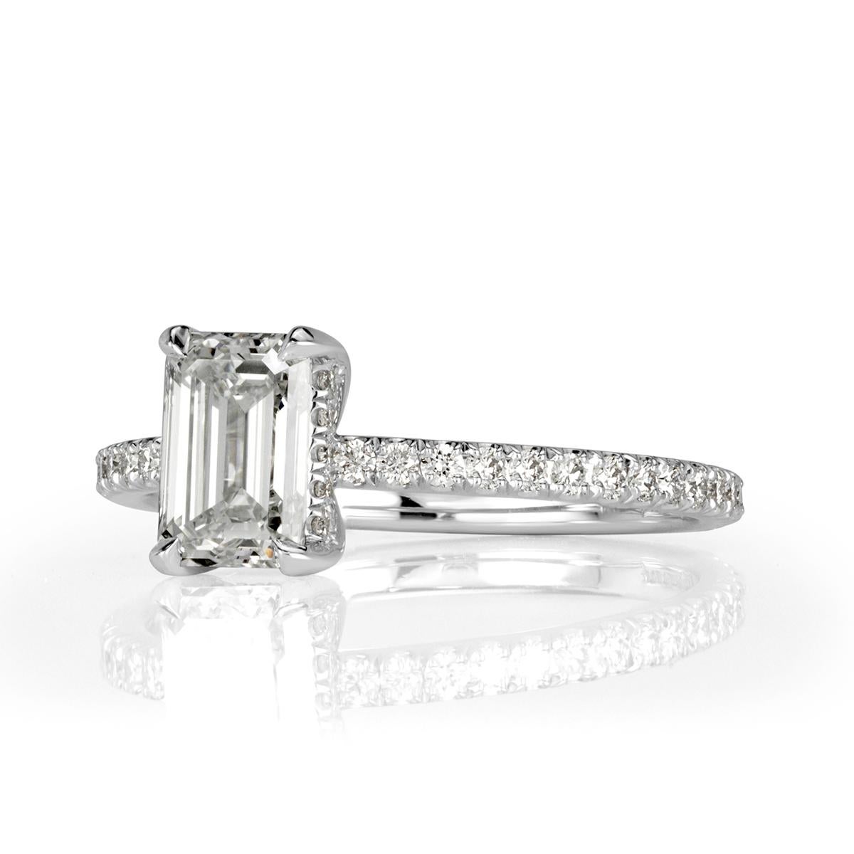 This ravishing diamond engagement ring showcases an exquisite 1.03ct emerald cut center diamond, GIA certified at F-VS1. It is poised atop a dainty micro pavé band and accented by a hidden halo of round brilliant cut diamonds studded onto the center