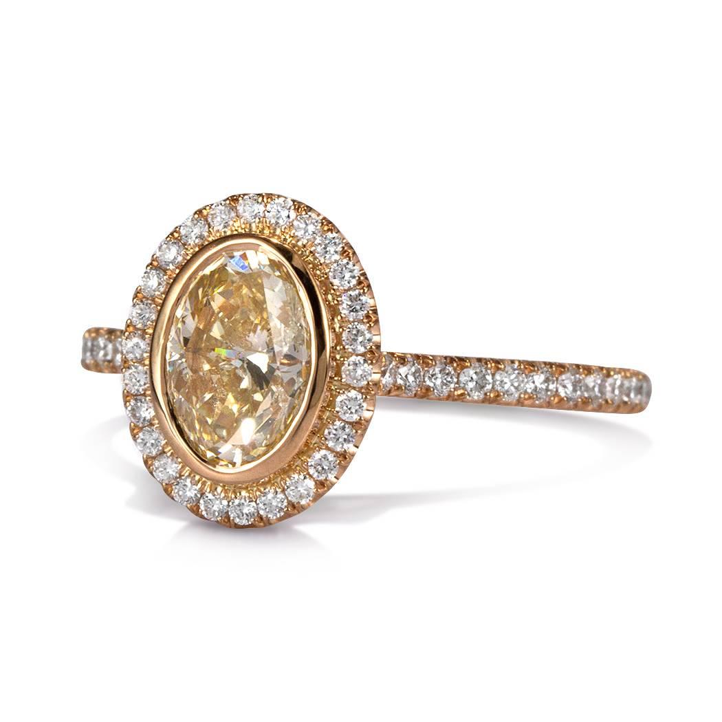 This stunning diamond engagement ring features a gorgeous oval cut center diamond, GIA certified at Fancy Light Brown Yellow-SI2. It is accented by a halo of peerless white round brilliant cut diamonds as well as one row of shimmering diamonds micro