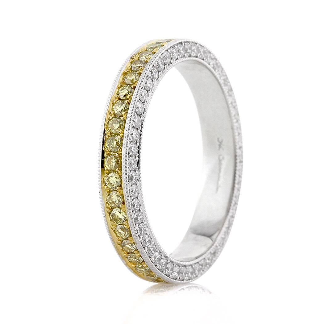 This ravishing diamond eternity band features one row of fancy yellow round brilliant cut diamonds set in the center and a row of white round brilliant cut diamonds on either side, all in a pave setting style. The diamonds are accented with