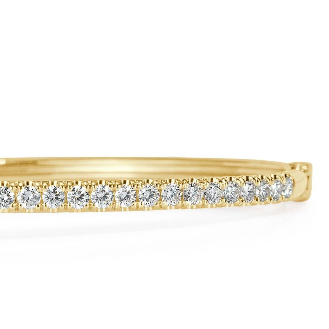 This striking modern diamond bangle is set with 1.45ct of round brilliant cut diamonds hand set in 14k yellow gold. All of the diamonds are perfectly matched and graded at E-F, VS1-VS2.