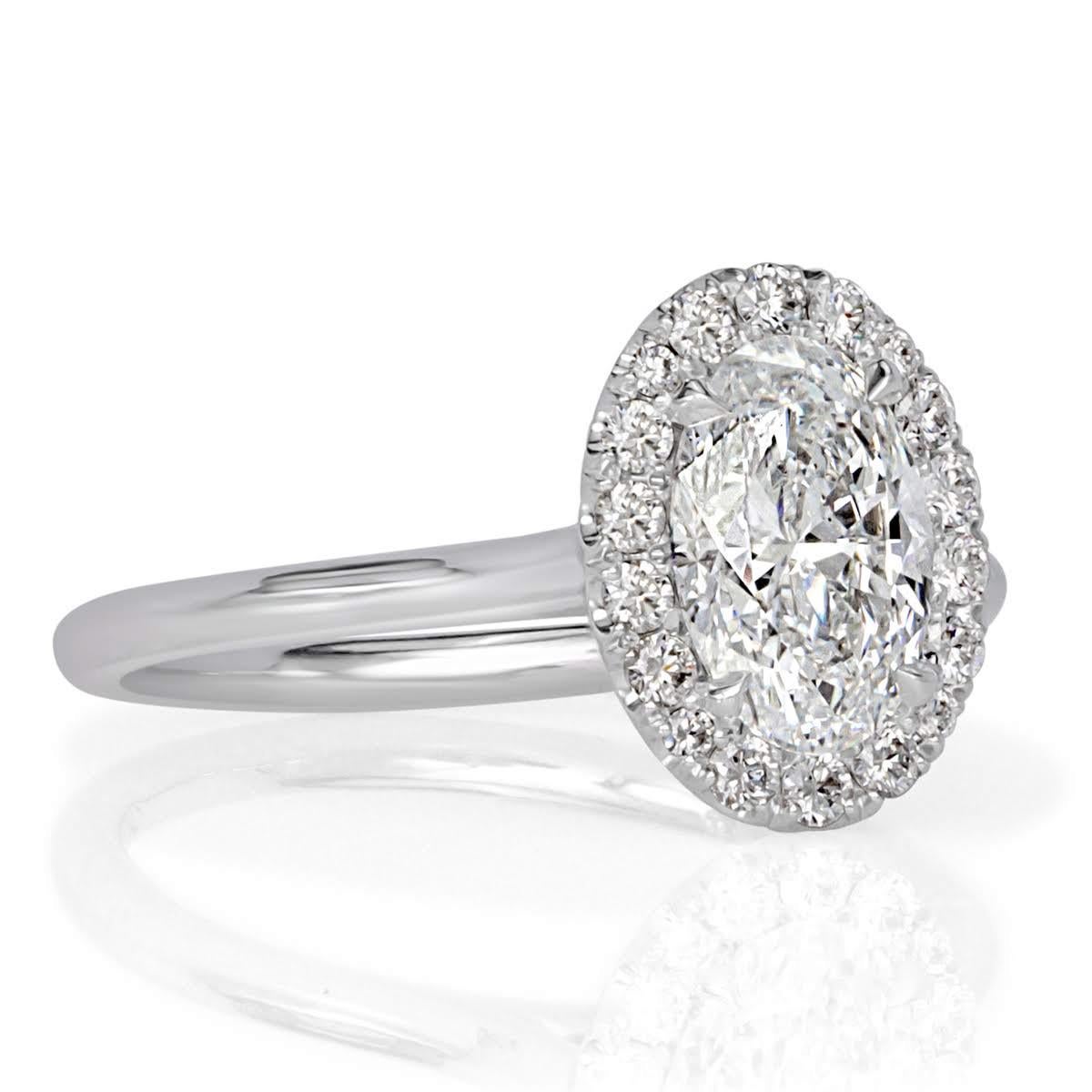 This truly ravishing diamond engagement ring features an exquisite 1.22ct oval cut center diamond, GIA certified at D in color, VS2 in clarity. It is exceptionally white and surrounded by a halo of small round brilliant cut diamonds as well as