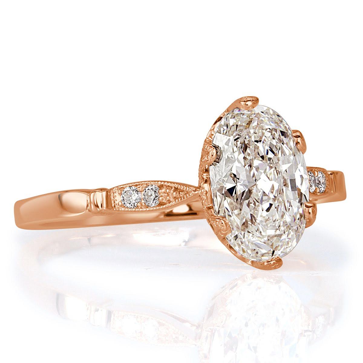 This exquisite diamond engagement ring showcases a gorgeous 1.50ct oval cut center diamond, GIA certified at I in color, VS1 in clarity. It is hand set in a beautiful antique, 18k rose gold setting style graced by two smaller round diamonds on