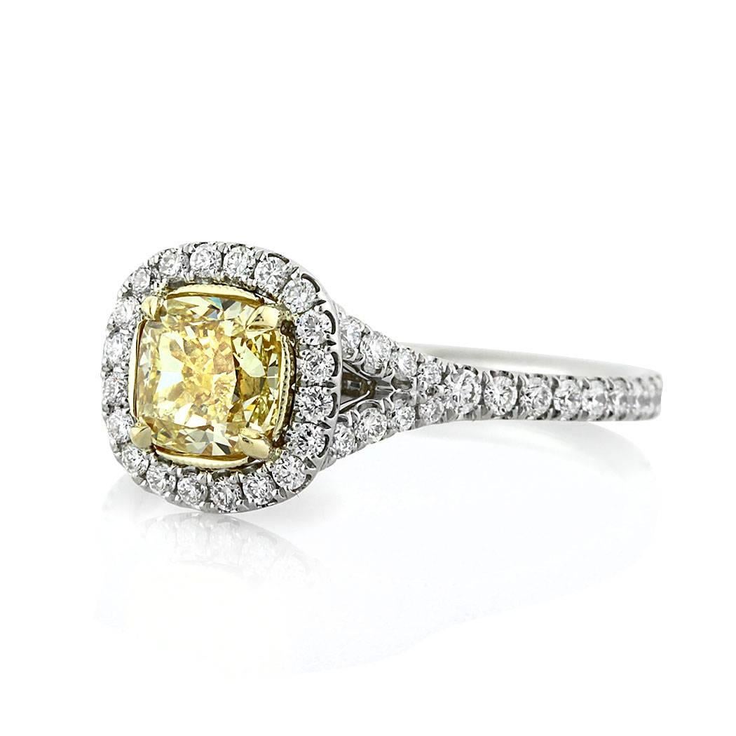 This gorgeous diamond engagement ring features a beautiful 0.92ct cushion cut center diamond, GIA certified at Fancy Yellow-VS2. It is accented by a gleaming halo of round brilliant cut diamonds as well as one row of peerless white round brilliant