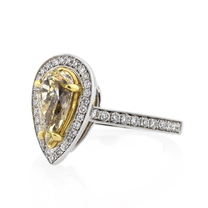 This beautiful diamond engagement ring showcases a stunning 1.01ct pear shaped center diamond, GIA certified at Fancy Light Yellow-I1. It is beautifully set in an 18k yellow gold basket surrounded by a halo of white round brilliant cut diamonds. For
