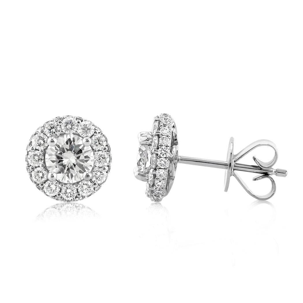 This pair of diamond stud earrings is set with 1.65ct of round brilliant cut diamonds graded at F-G, VS1-VS2. They feature a larger round diamond at the center surrounded by a halo of bright diamonds for added brilliance. They are handset in a
