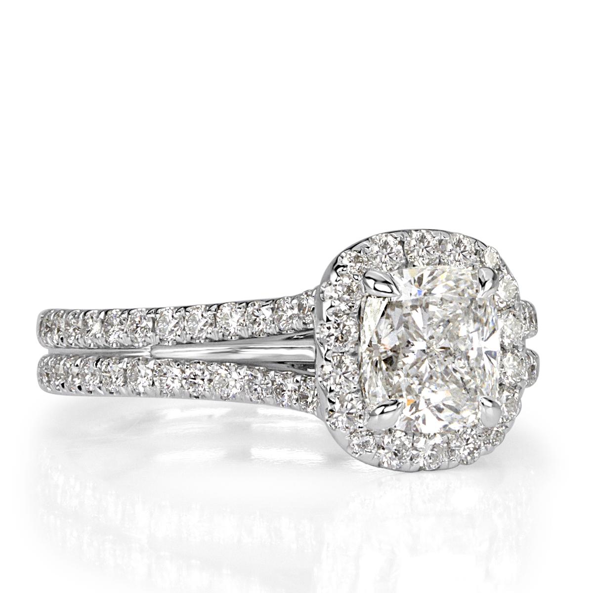 Custom made in high polish platinum, this stunning diamond engagement ring features a beautiful 1.01ct cushion cut center diamond, GIA certified at F-SI1. It is accented by a halo of round brilliant cut diamonds as well as one row of shimmering