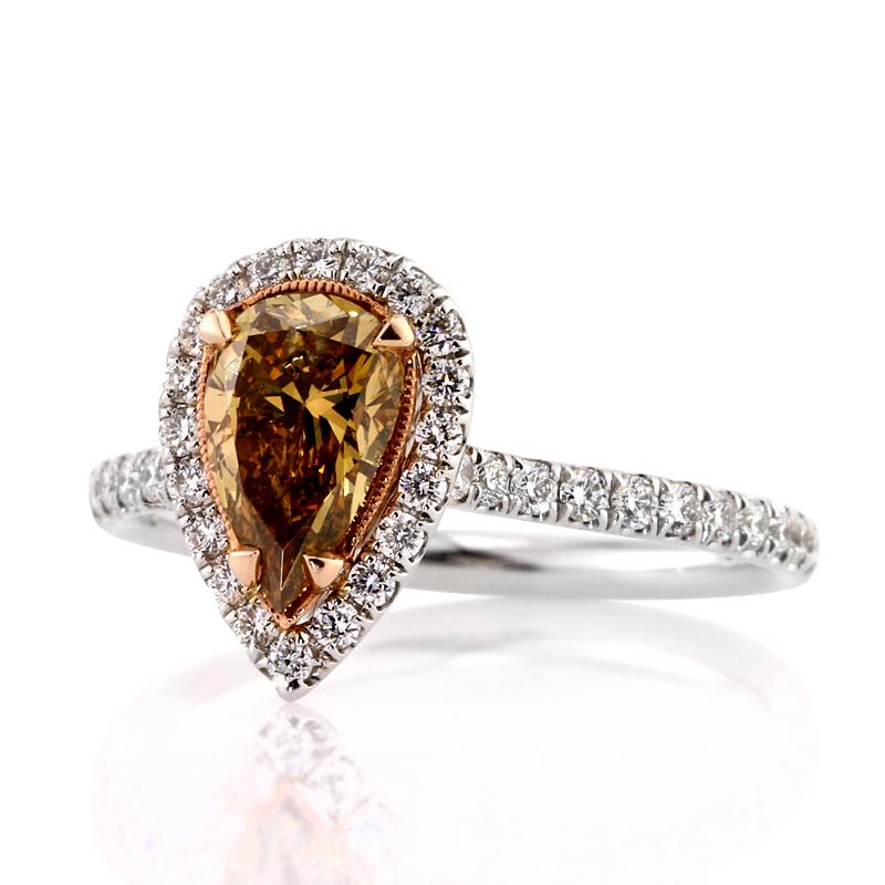 This unique diamond engagement ring features an exquisite 1.02ct pear shaped center diamond, GIA certified at Fancy Dark Brown Orange Yellow-I1. It is meticulously hand set in a rose gold center basket with a matching halo of white round brilliant