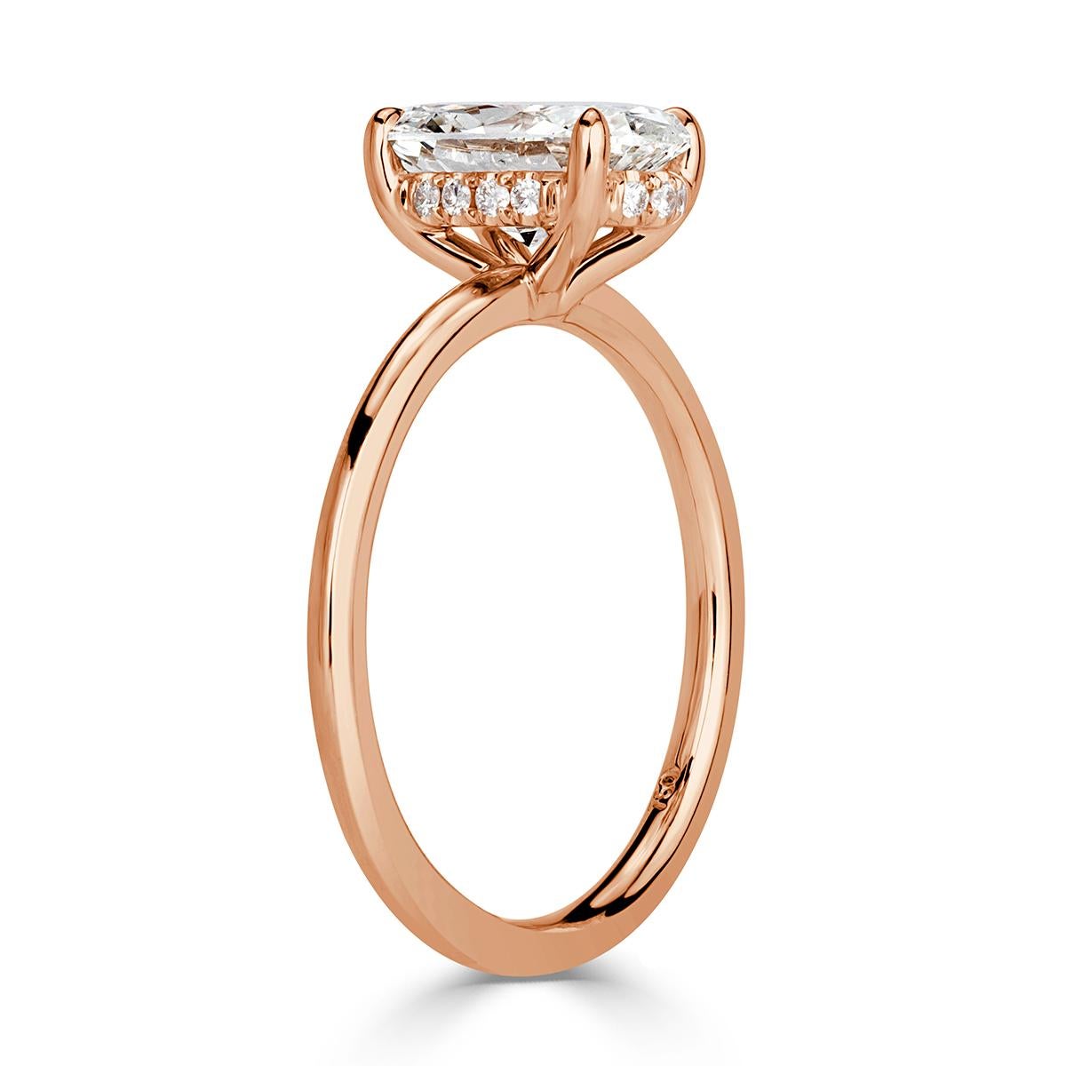 Custom created in an 18k rose gold solitaire setting style, this ravishing diamond engagement ring showacses a beautiful 1.70ct oval cut center diamond, GIA certified at I-VS2. It is accented by a hidden halo of round brilliant cut diamonds studded