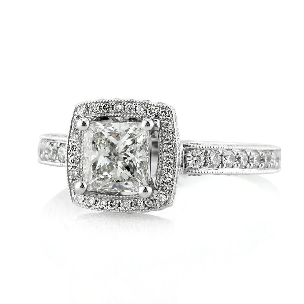This beautiful diamond engagement ring features a 1.01ct princess cut center diamond, GIA certified at H-VS2. It is accented by a two sided halo of round brilliant cut diamonds as well as one row of shimmering diamonds pavé set around the 18k white