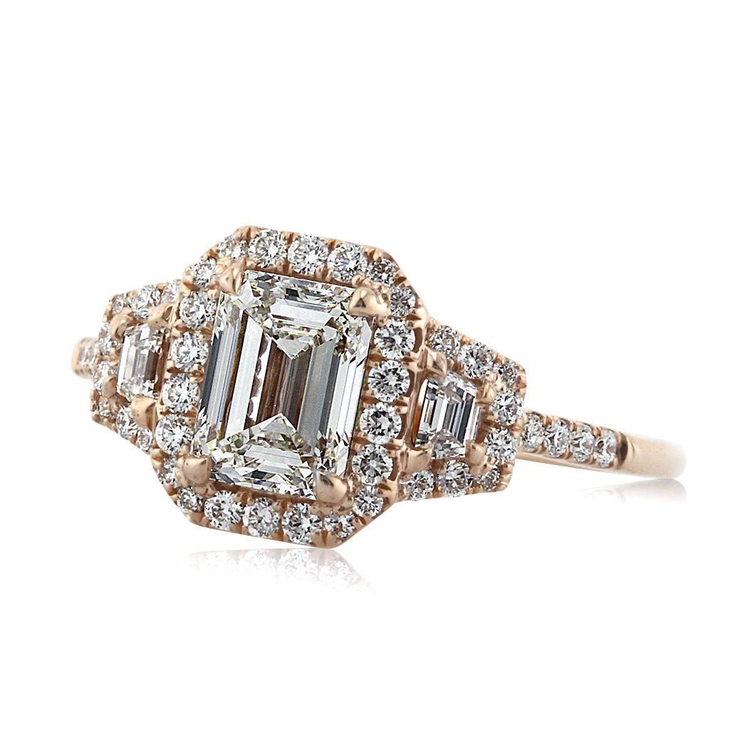 This beautiful diamond engagement ring is set with a 1.20ct emerald cut center diamond, GIA certified at H-VVS1. It is accented by a halo of round diamonds and flanked by two step cut trapezoids, which are also surrounded by round brilliant cut