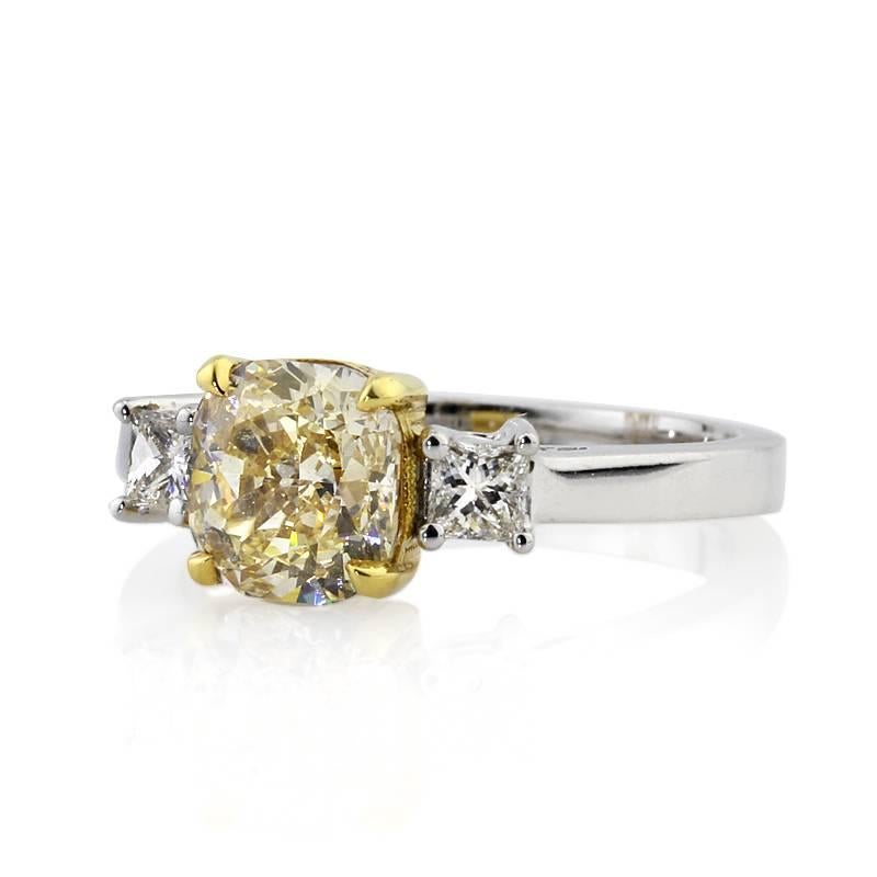 This elegant diamond engagement ring showcases a stunning 1.78ct cushion cut center diamond, EGL certified at Fancy Yellow-VS2. It is exquisitely prong set in an 18k yellow gold center basket and accented by two colorless princess cut diamonds on