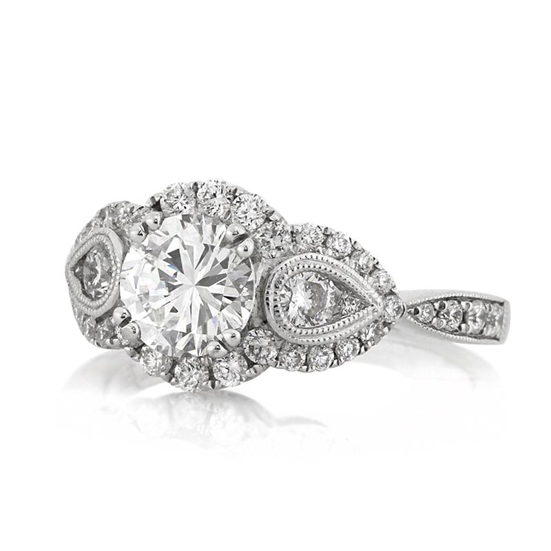 This dazzling, three-stone diamond engagement ring showcases a mesmerizing design of round brilliant cut diamonds hand set in 18k white gold. A stunning 1.02ct round brilliant cut diamond is set at the center, EGL certified at D-VS1. It is accented