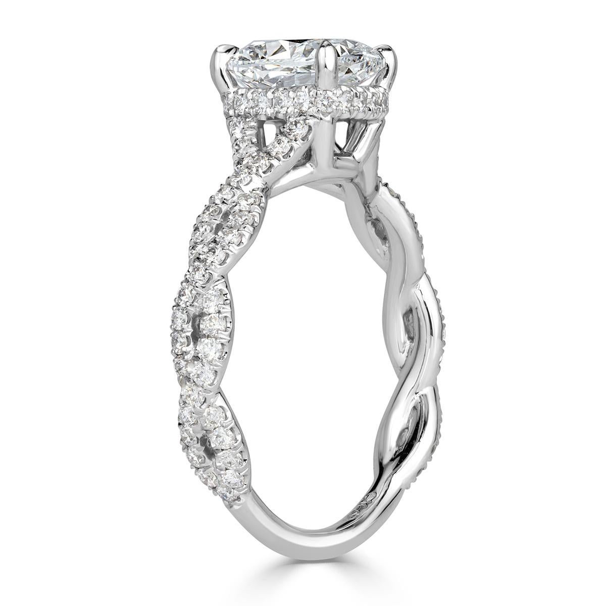 This mesmerizing diamond engagement ring showcases a stunning 1.50ct cushion cut center diamond, GIA certified at E-SI2. It is accented by a hidden halo and poised atop a feminine shank featuring a twist design embellished with round brilliant cut