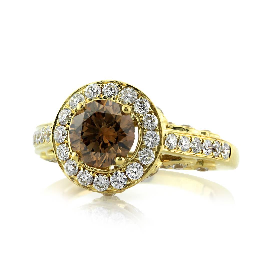 This magnificent diamond ring showcases a 1.13ct round brilliant cut center diamond, EGL certified at Fancy Dark Brown-SI2. It is accented by a shimmering halo of round brilliant cut diamonds set in a pavé setting style. The 18k yellow gold shank