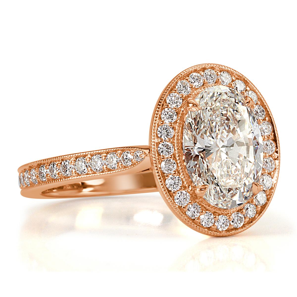This feminine diamond engagement ring features a beautiful 1.85ct oval cut center diamond, GIA certified at I-VVS2. It is bezel set to perfection in 18k rose gold and accented by a halo of round brilliant cut diamonds as well as sparkling diamonds