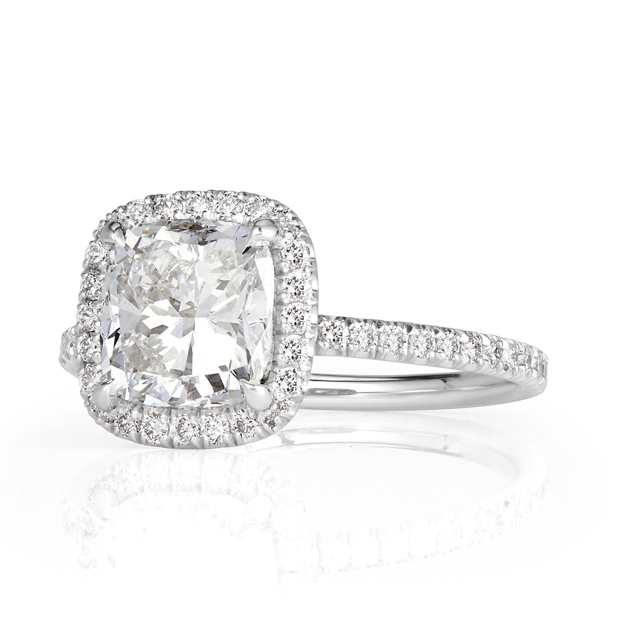 Created in platinum, this mesmerizing diamond engagement ring showcases a stunning 2.01ct cushion cut centerd diamond, GIA certified at F-SI1. It is accented by a matching halo of round brilliant cut diamonds as well as one row of sparkling diamonds