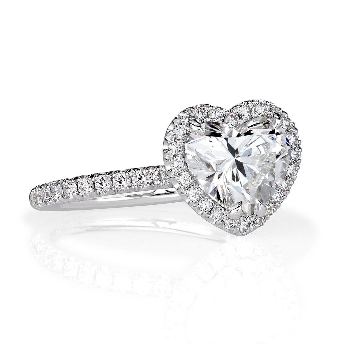This exquisite diamond engagement ring showcases a 2.00ct heart shaped center diamond, GIA certified at H-VS2. It is accented by a matching halo of round brilliant cut diamonds as well as one row of sparkling diamonds micro pavé set down the band.