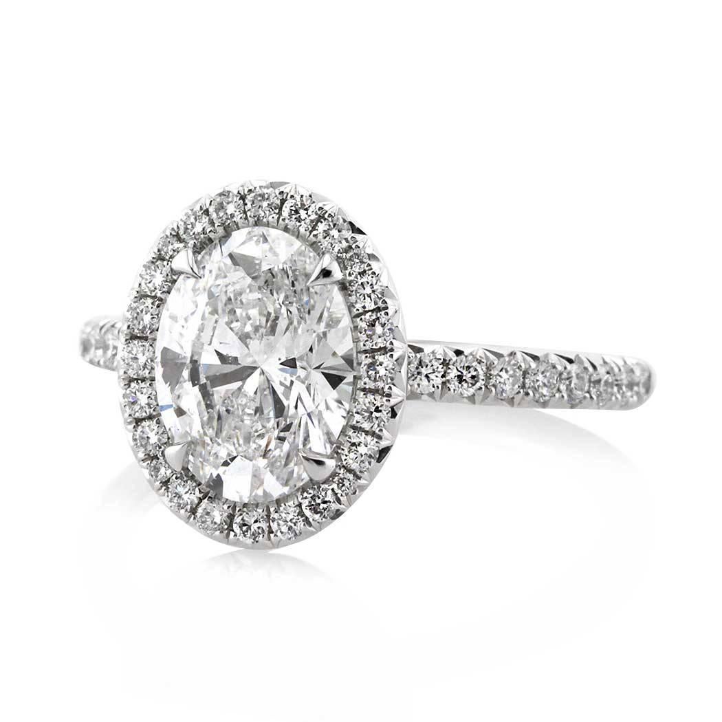 This 2.56ct diamond engagement ring is set with a 2.01ct oval cut center diamond GIA certified at D, SI2. It is beautifully handcrafted on a designer platinum setting and accented by a halo of round brilliant cut diamonds with glittering diamonds
