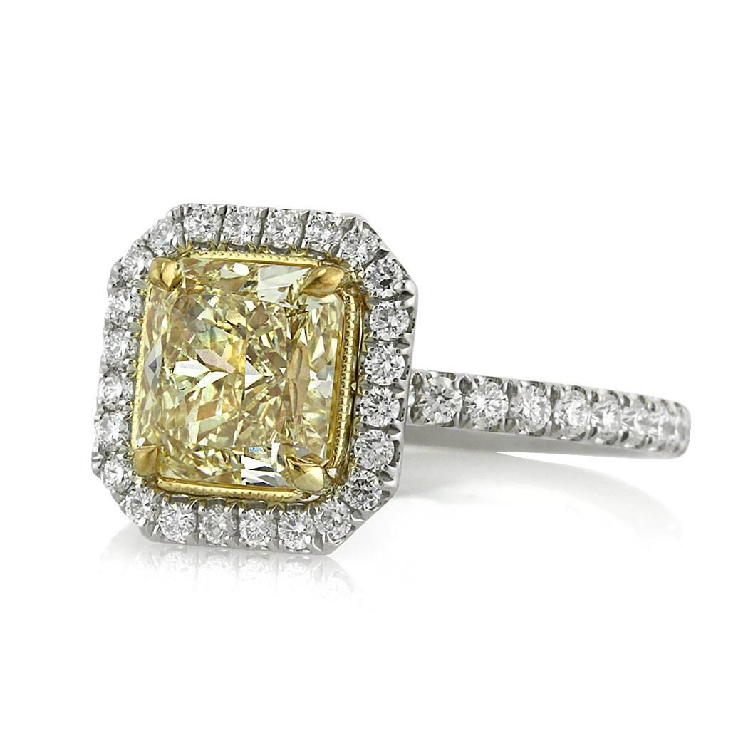 This gorgeous diamond engagement ring features a superb 2.01ct radiant cut center diamond, GIA certified at Fancy Intense Yellow-VVS2. It is accented by a shimmering halo of white round brilliant cut diamonds as well as one row of sparkling round