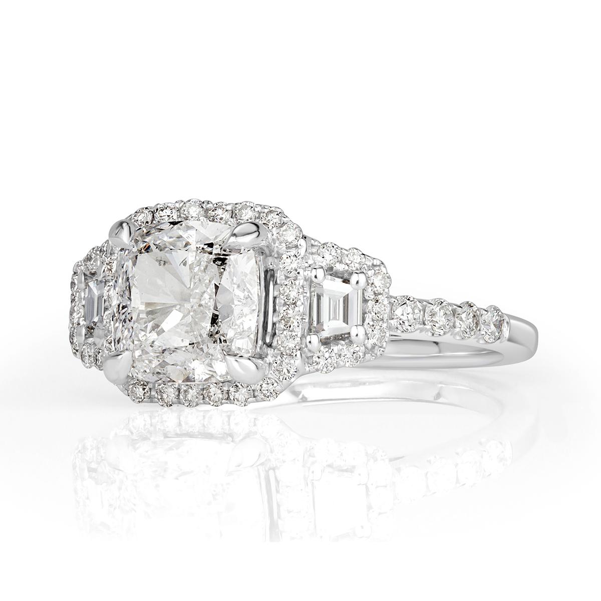 This astonishing diamond engagement ring showcases a superb 2.01ct cushion cut center diamond, IGI certified at G-SI2. It is flanked by two trapezoid cut diamonds on either side and for maximum sparkle, each of the center diamonds is surrounded by a