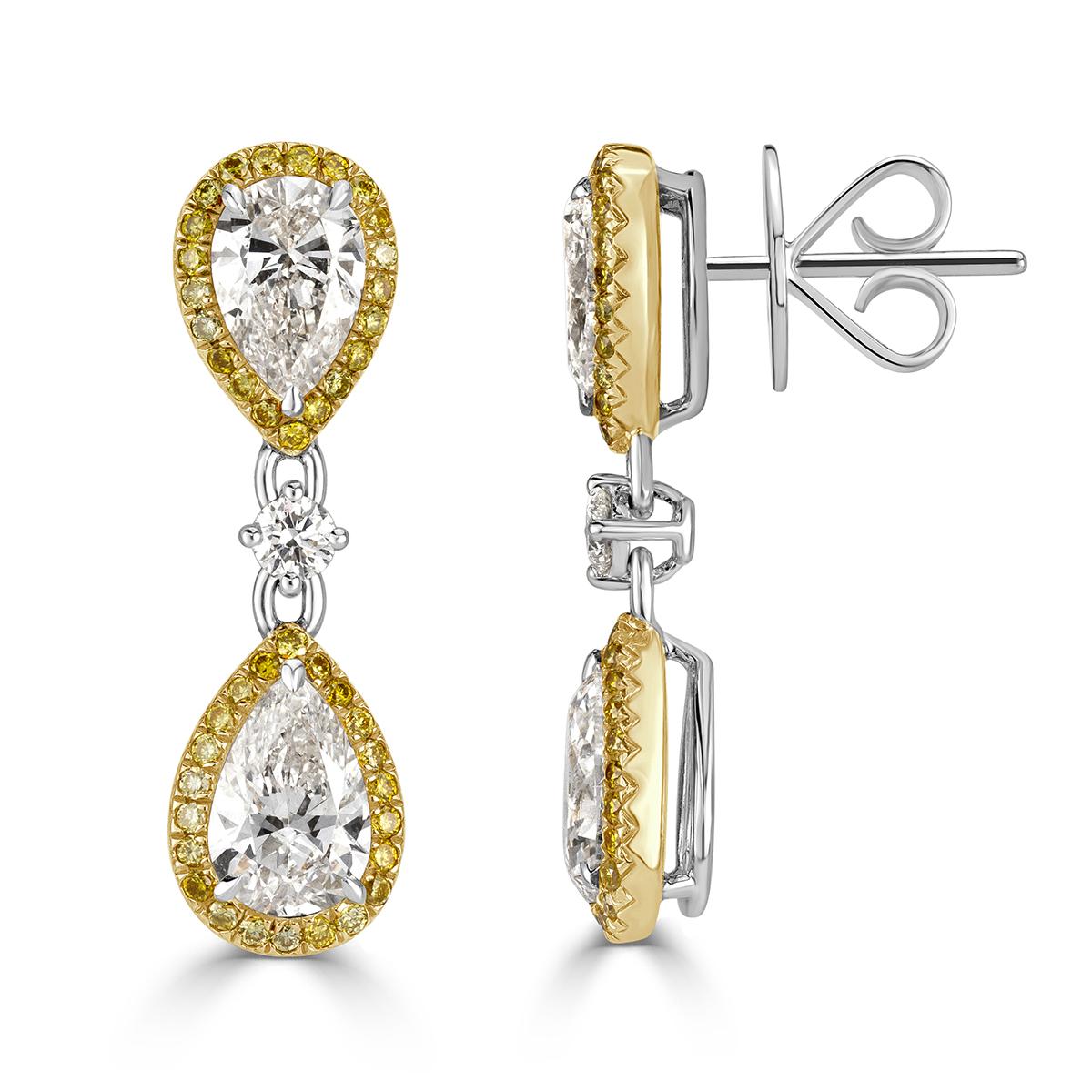 This glamorous pair of diamond dangle earrings showcases an exquisite design of larger pear shaped diamonds each complimented by a dainty micro pavé halo of fancy yellow diamonds. The diamonds total 3.29ct in weight ( 2.71ct Pear Shapes + 0.58ct