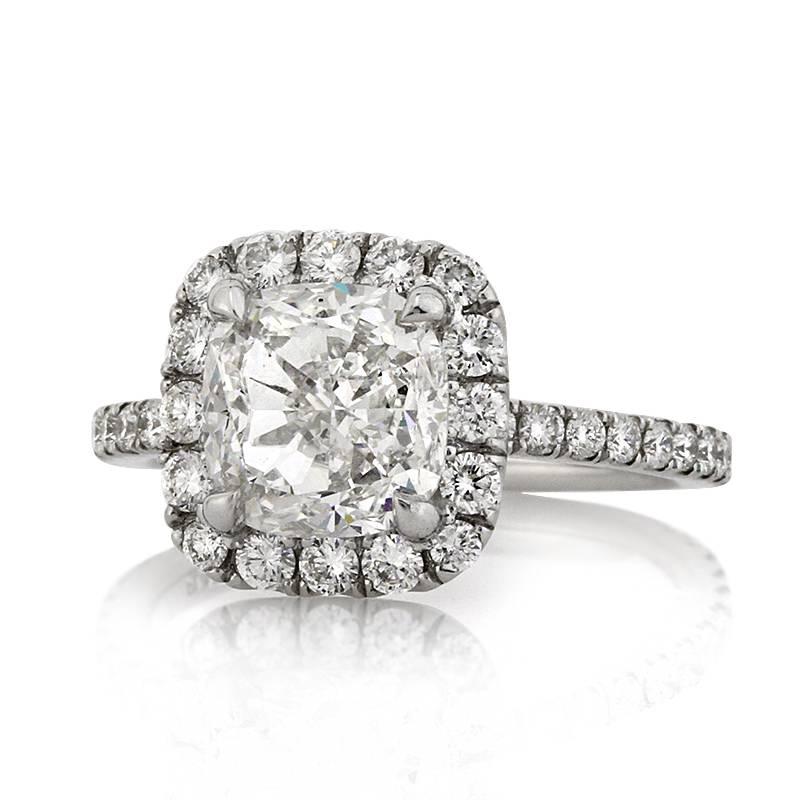 This spectacular diamond engagement ring is set with a stunning 3.01ct cushion cut center diamond, GIA certified at F-VS1. It is surrounded by a halo of smaller round brilliant cut diamonds as well as one row of micro pavé diamonds set around the