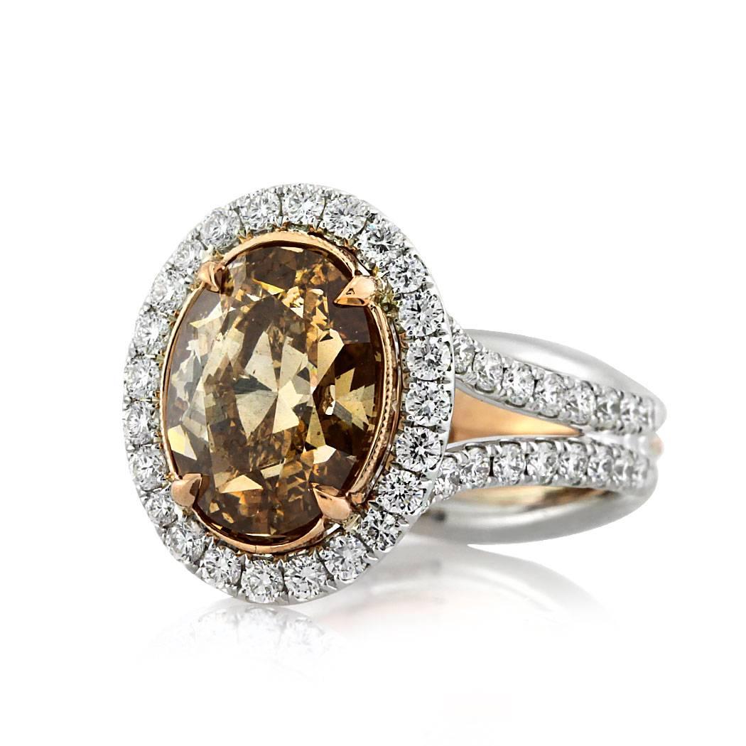 This beautiful diamond engagement ring features a gorgeous 3.28ct oval cut center diamond, GIA certified at Fancy Brown Yellow-SI1. It is set in a hand engraved, rose gold center basket and surrounded by a dazzling halo of peerless white round