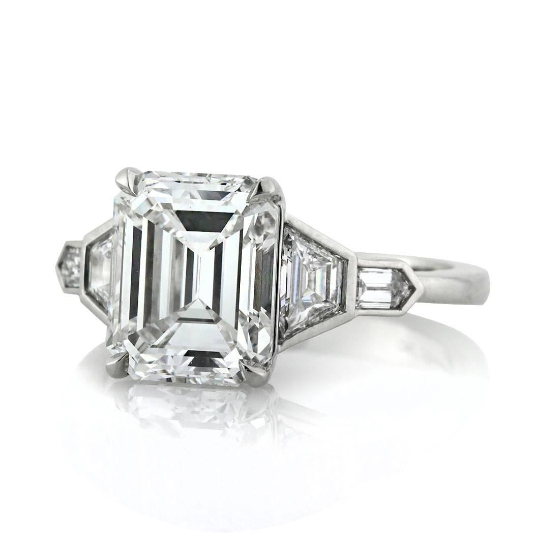 Custom created in high polish platinum, this superb diamond engagement ring showcases a unique 3.74ct emerald cut center diamond, GIA certified at F-VVS2. It is flanked by two trapezoid and bullet cut diamonds on either side. The accent diamonds