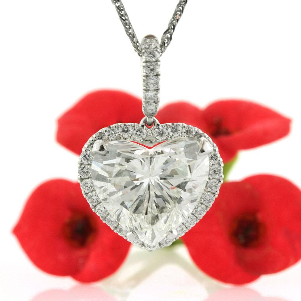 This diamond pendant necklace showcases a superb 4.30ct heart shaped center diamond, HRD certified at I-SI2. It is surrounded by a halo of round brilliant cut diamonds and the bail is also studded with sparkling diamonds for added brilliance in this