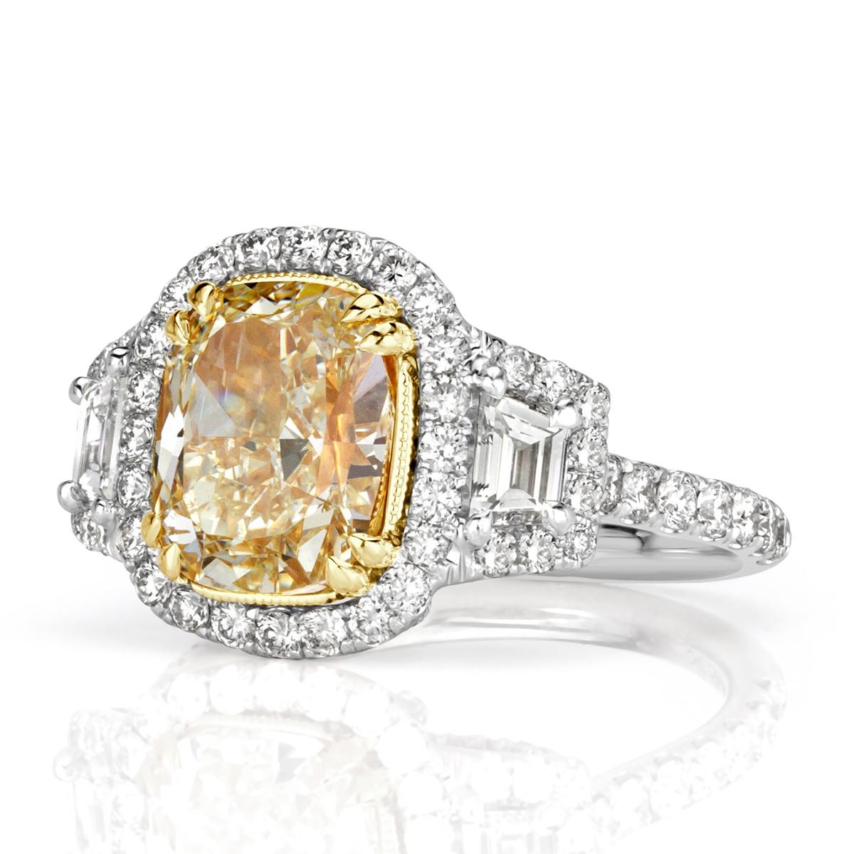 This gorgeous piece features a one-of-kind 3.33ct cushion cut center diamond, GIA certified at fancy light yellow in color, VS2 in clarity. It radiates a vibrant yellow hue and has amazing measurements of 9.54 x 7.60mm. It is flanked by two