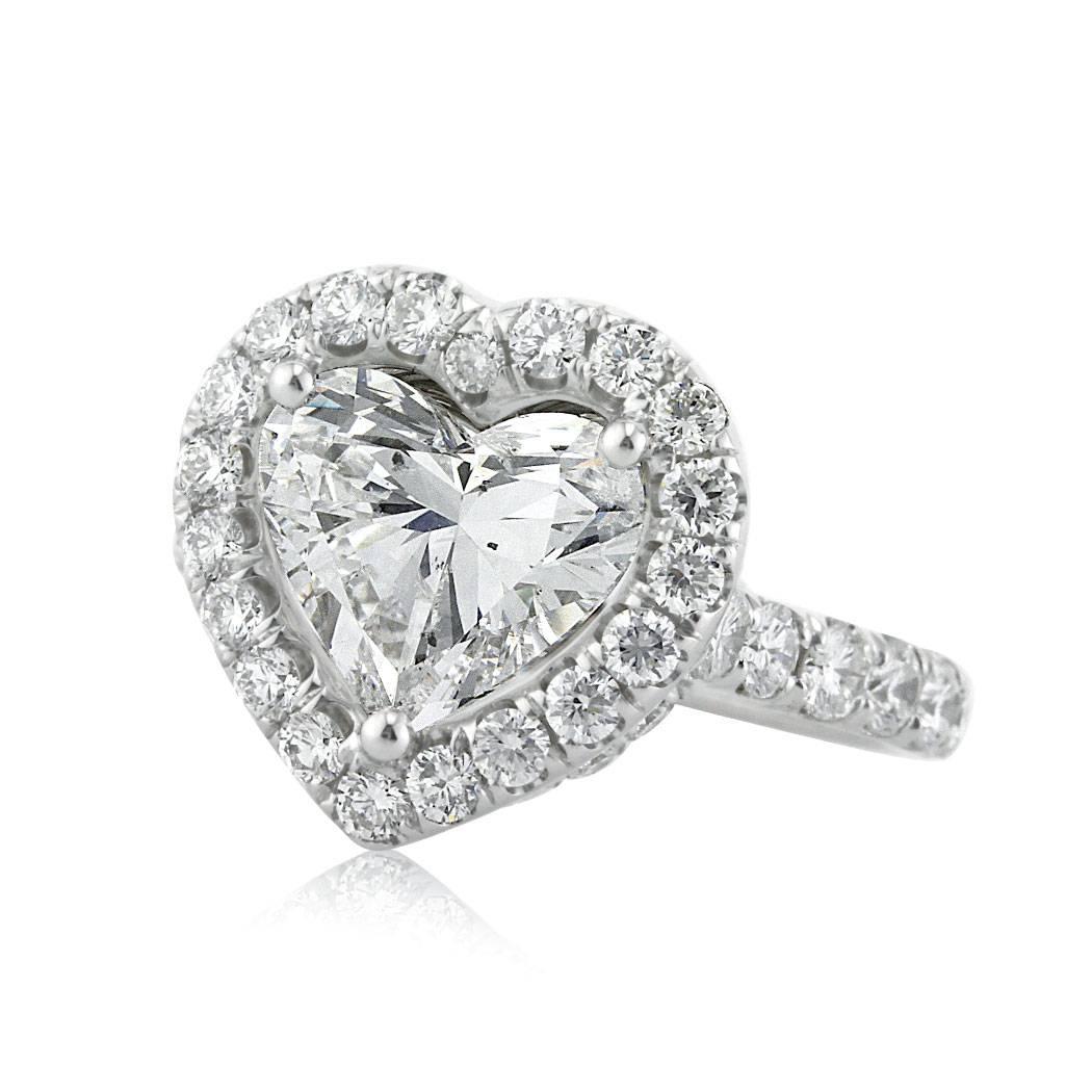 This platinum and diamond engagement ring is set with a 3.13ct heart shaped center diamond AGS certified at D, SI2. It is accented by a halo of round brilliant cut diamonds and micro pave set diamonds on the shank. All of the side diamonds are