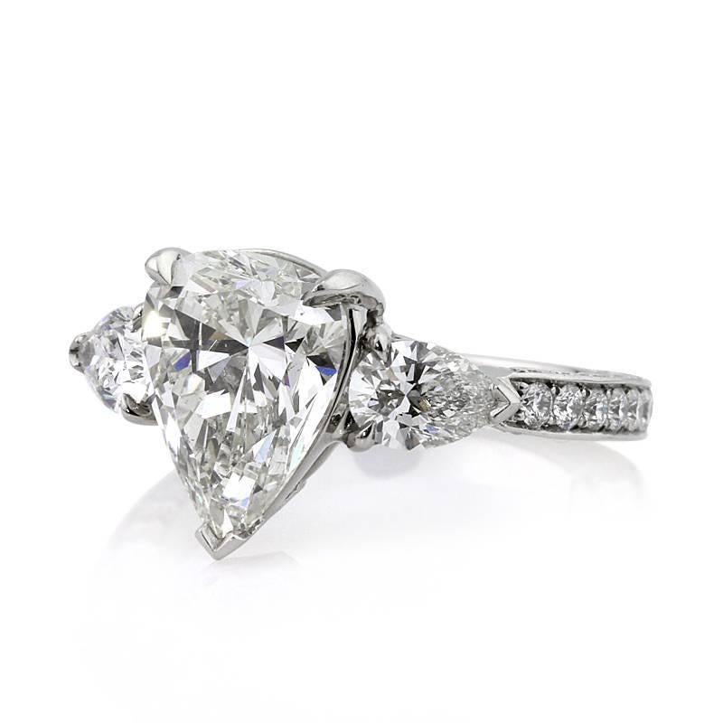 This jaw-dropping diamond engagement ring showcases a superb 3.04ct pear shaped center diamond, EGL certified at H-VS1. It is accented by two smaller pear shaped diamonds on either side as well as one row of shimmering diamonds set on all three