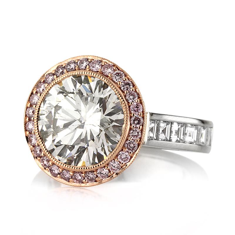 This spectacular diamond engagement ring showcases a unique 4.40ct round brilliant cut center diamond, EGL certified at I-SI2. It is surrounded by a halo of fancy pink round brilliant cut diamonds embedded into hand milgrain detail. For added