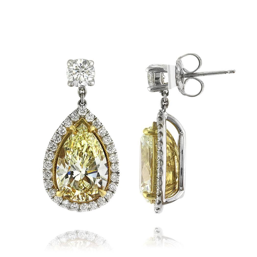 This incredible pair of diamond earrings features two large pear shaped diamonds totaling 7.85ct and GIA certified at Light Yellow-SI1. The center diamonds are set in hand engraved 18k yellow gold baskets and accented by a halo of peerless white