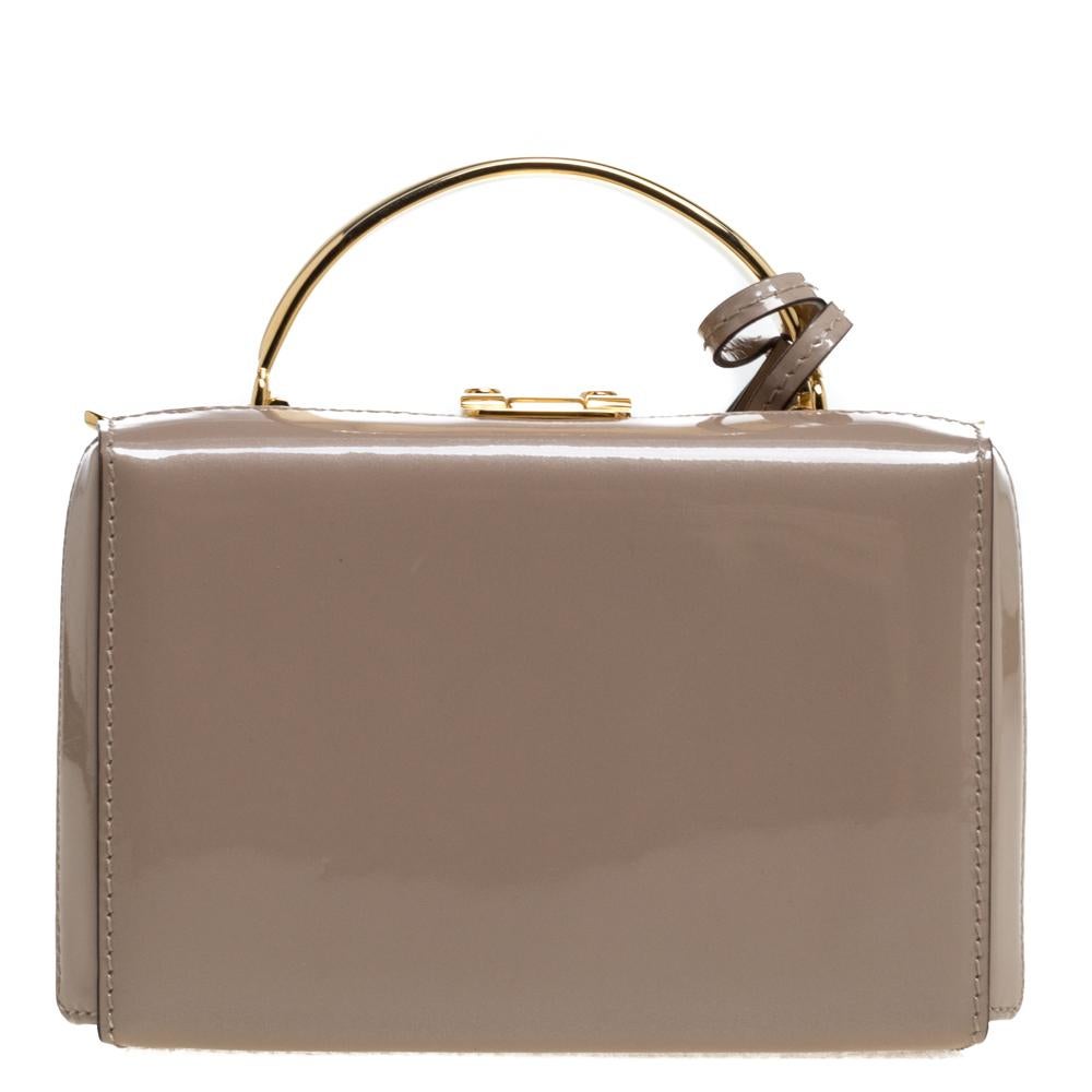 This creation from Mark Cross is a structured bag made with patent leather. It comes with a detachable leather crossbody strap. The bag features a gold-tone top handle and metal closure on which the brand logo is engraved. This mini Grace Box bag is