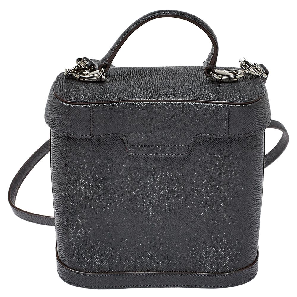This Mark Cross bag is the epitome of fun and feminine style. This multipurpose leather bag would go perfectly for any occasion. It has a structured shape with a top that resembles a lid. The black-hued bag is held by a top handle and a shoulder