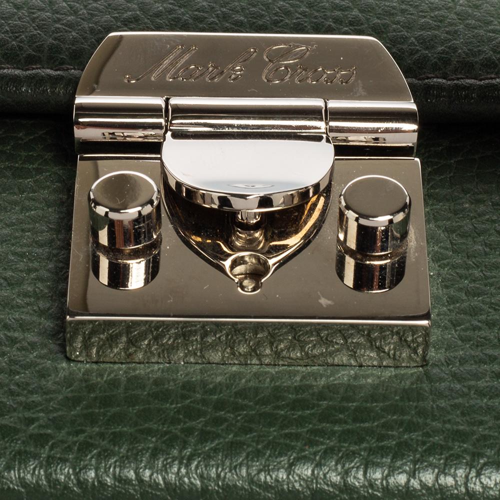 This small Grace Box bag is a statement-making creation you'll love to own! This elegant bag from Mark Cross features a green leather exterior, a top handle, and silver-toned metal closure on which the brand logo is engraved. This bag is eternally