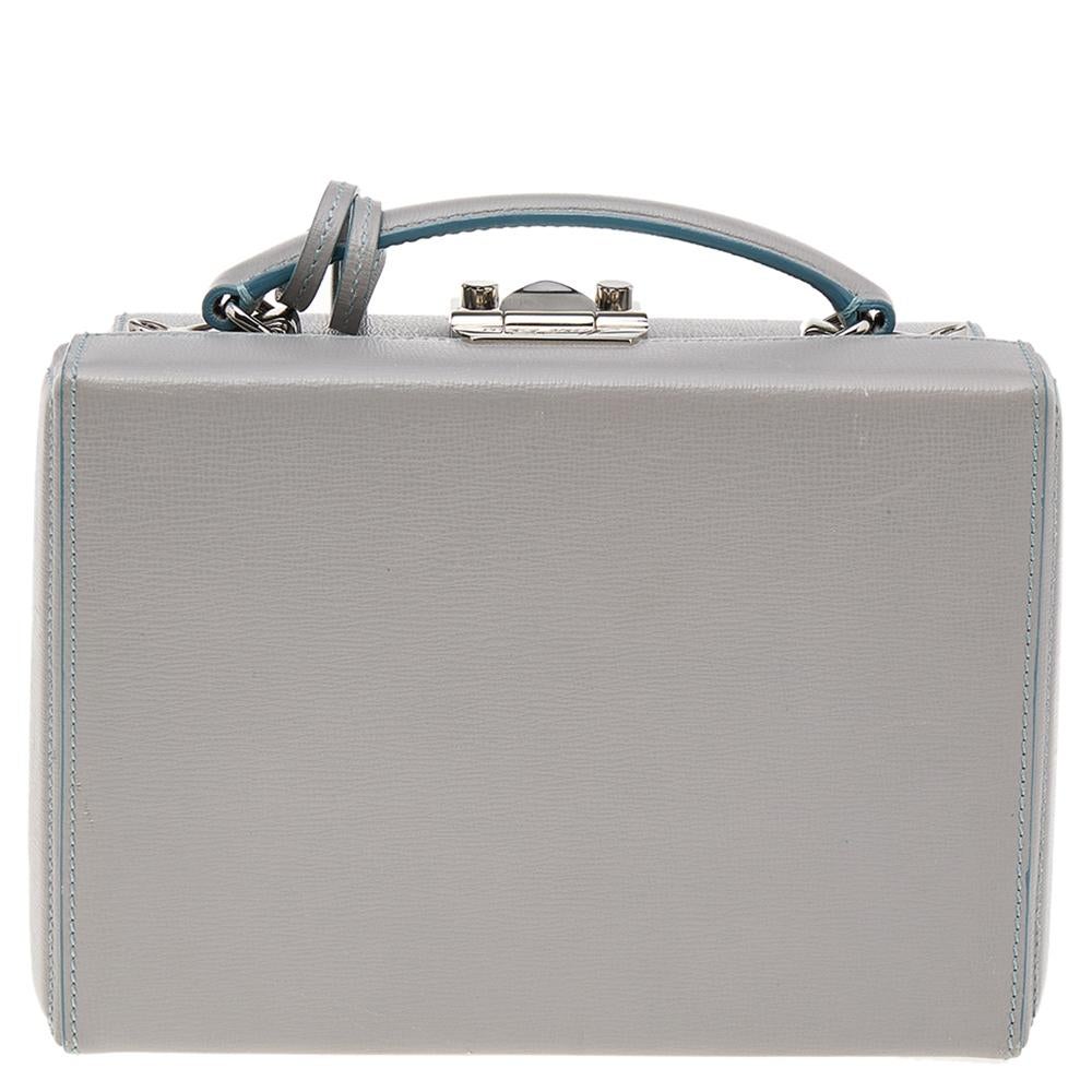 This small Grace Box bag is a statement-making creation you'll love to own! This elegant bag from Mark Cross features grey leather on the exterior, a top handle, and silver-toned metal closure on which the brand logo is engraved. This bag is