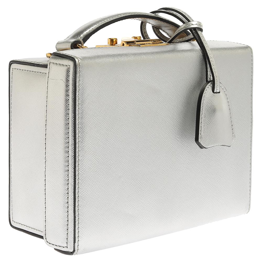 Mark Cross's Grace box bag is inspired by the luggage used by Grace Kelly in the iconic film, Rear Window. It is made from lustrous silver leather. The bag comes with a top handle, a detachable leather strap, and top hardware closure with the