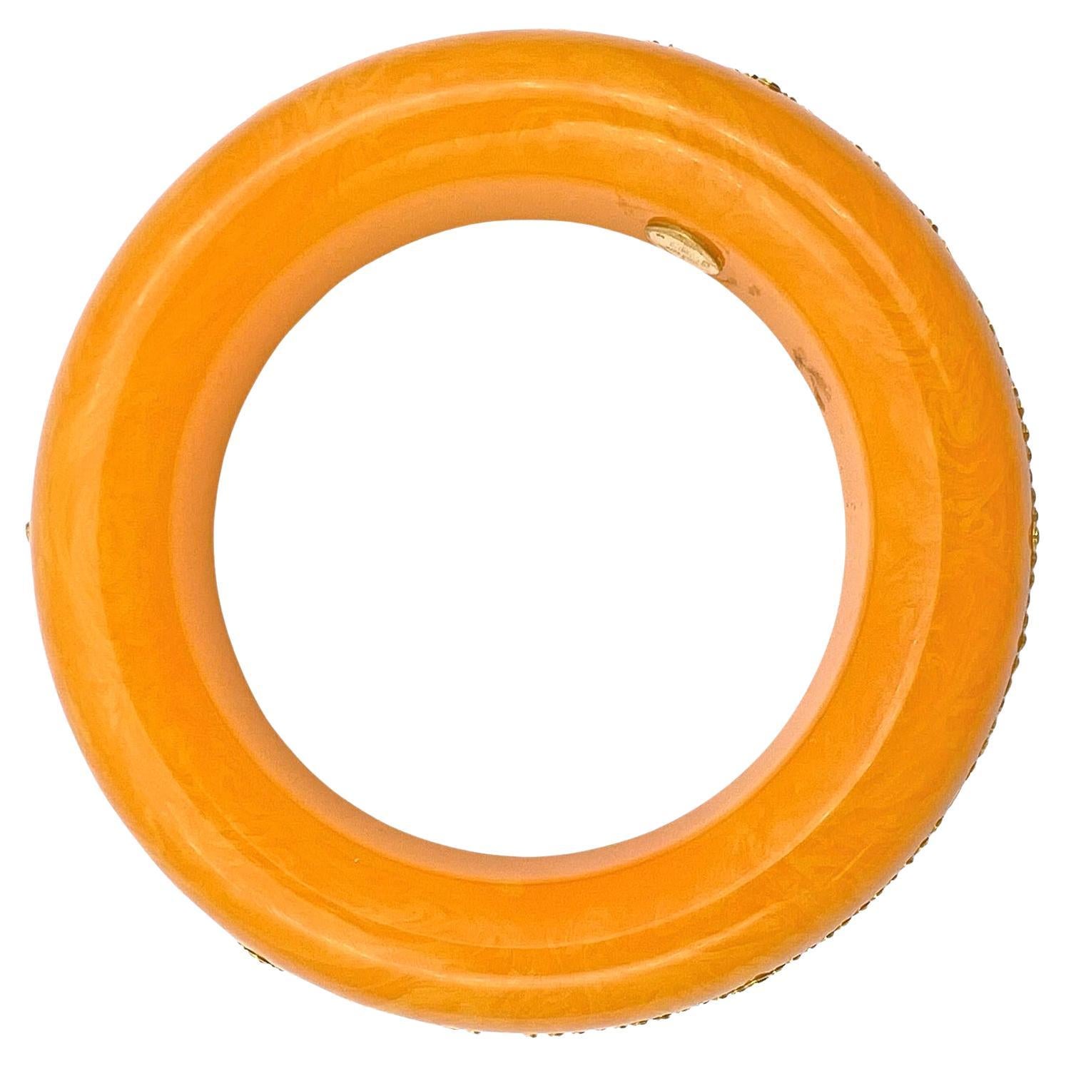 Crafted from orange vintage bakelite, this Mark Davis bangle bracelet features a geometric pattern of two intersecting rows of round brilliant-cut yellow sapphires in larger and smaller sizes.  Each yellow sapphire is individually bezel-set in 18k