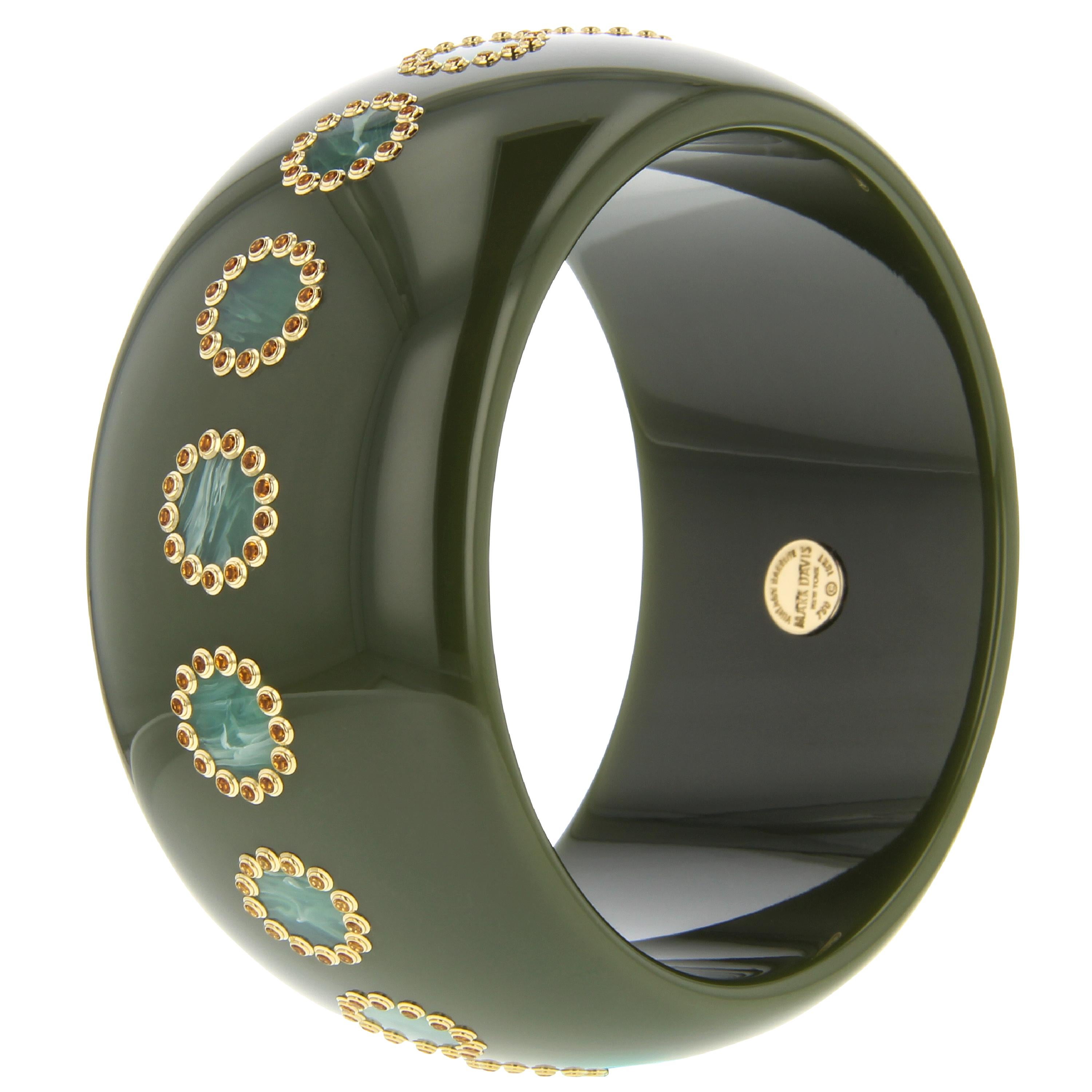 This incredible Mark Davis bangle was created from olive green, unmarbled, vintage bakelite. The bangle has been inlaid with a light greenish-blue bakelite with remarkable marbling. Each inlaid circle is surrounded by a frame of individually set