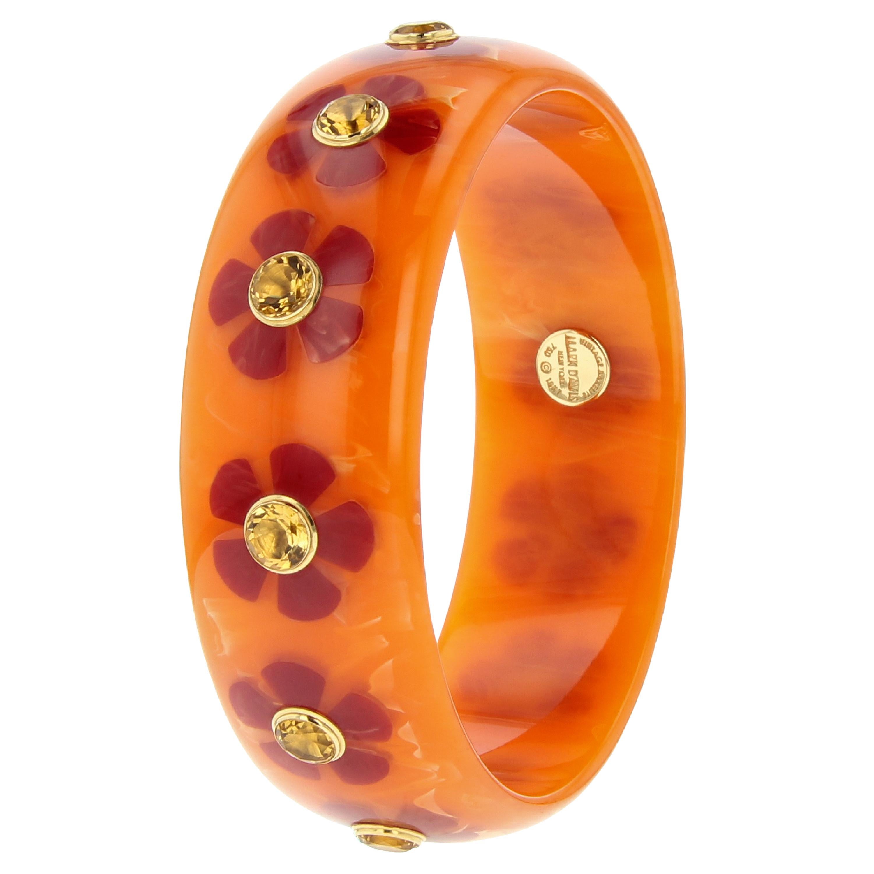 This fun and striking Mark Davis bangle was made from vintage, subtly marbled, orange bakelite. The bangle has been inlaid with burgundy bakelite flowers that have been randomly scattered around the bracelet. The flowers all feature a large