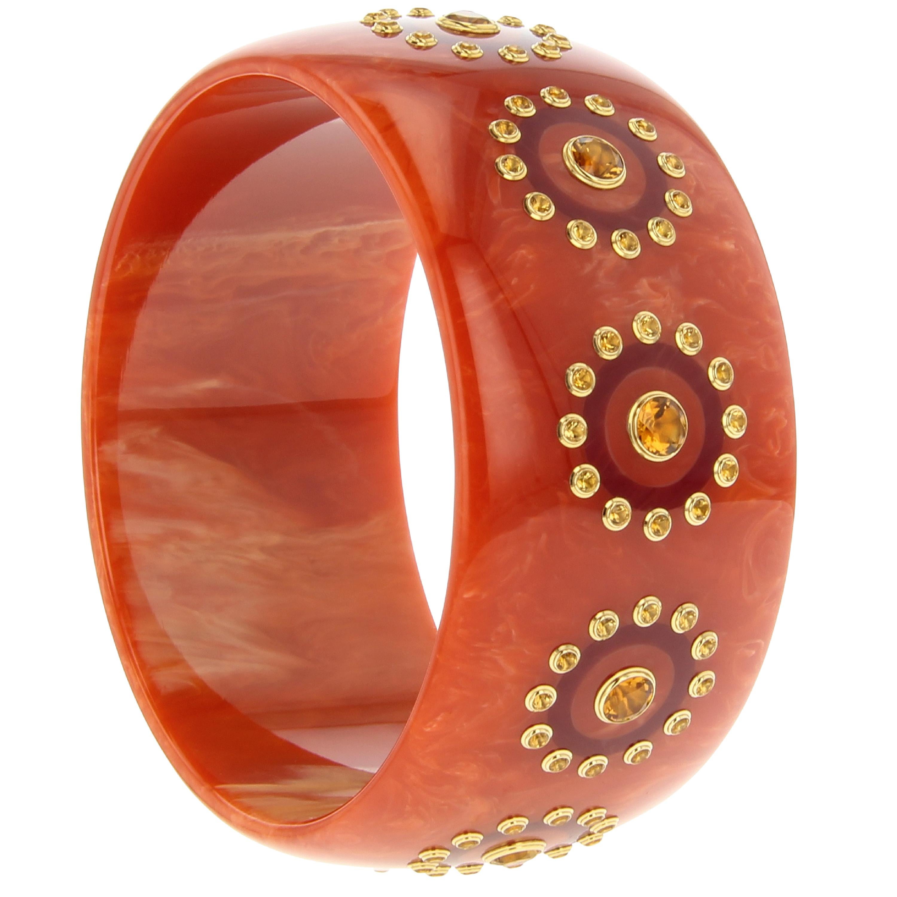 This stunning Mark Davis bangle was created from vintage bakelite with subtle burgundy rings inlaid within a border of perfectly matched citrine. The center of each ring features a larger single citrine mounted in an 18k yellow gold bezel.

Full